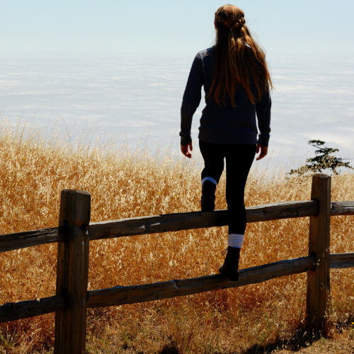 Photo of a woman stepping over a fence.